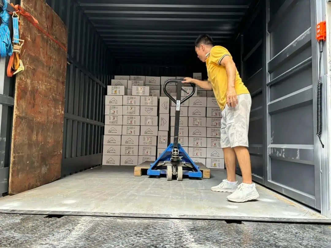 Person loading boxes with pallet jack in truck.
