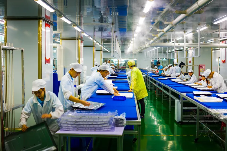 Workers assembling electronics in a factory setting.